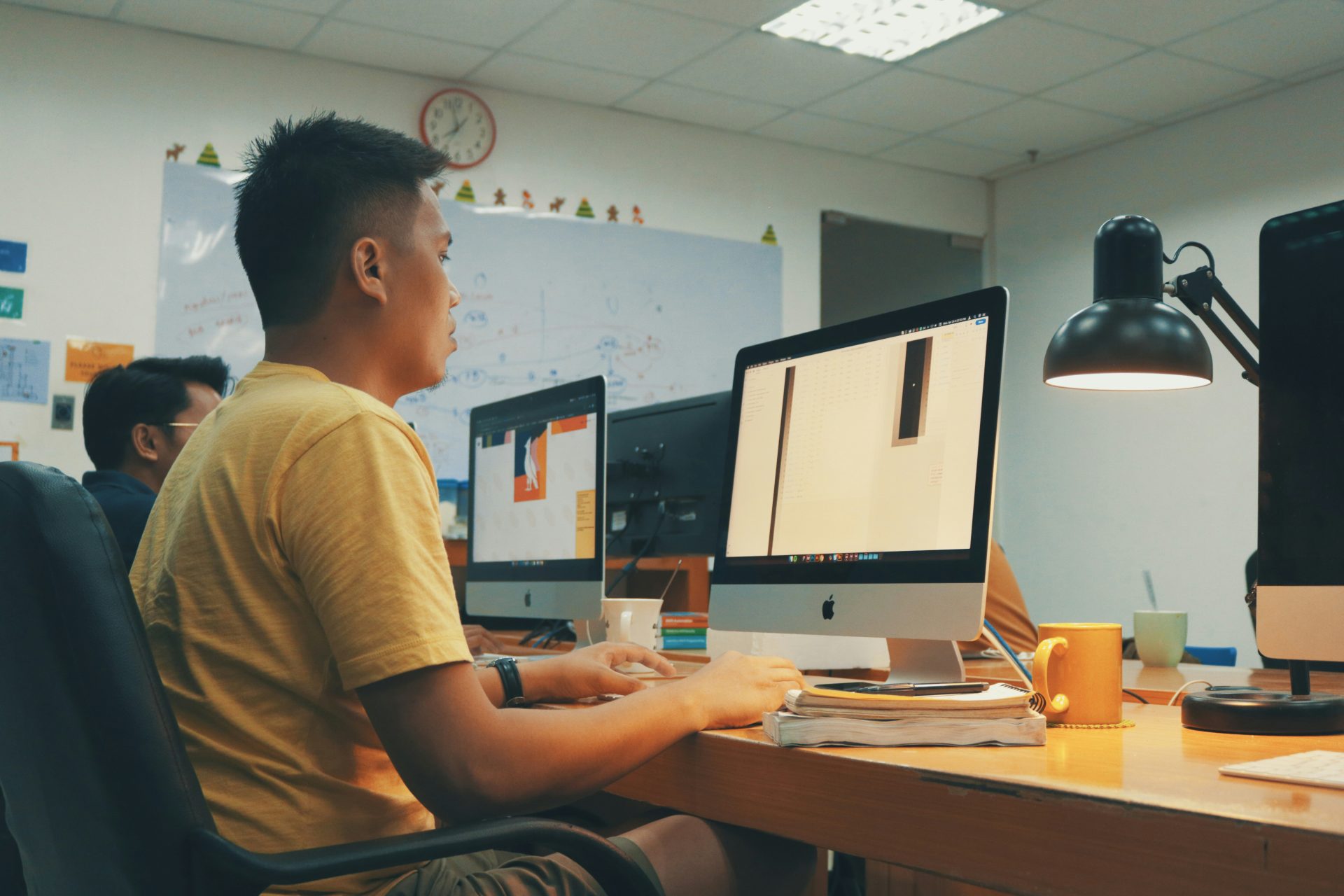 homme utilisant un ordinateur de bureau Apple dans une pièce à côté d'un autre homme